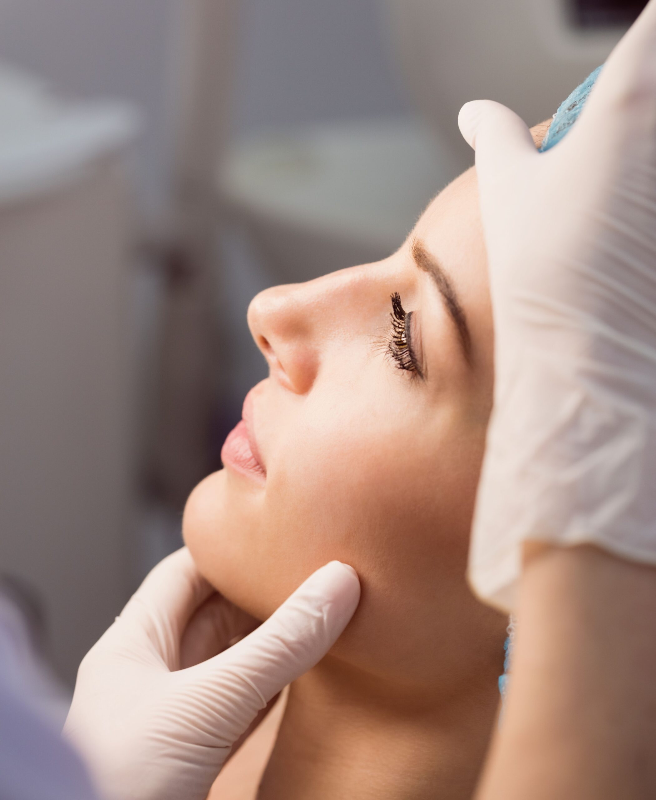 Hands of doctor examining womans face for cosmetic treatment at clinic