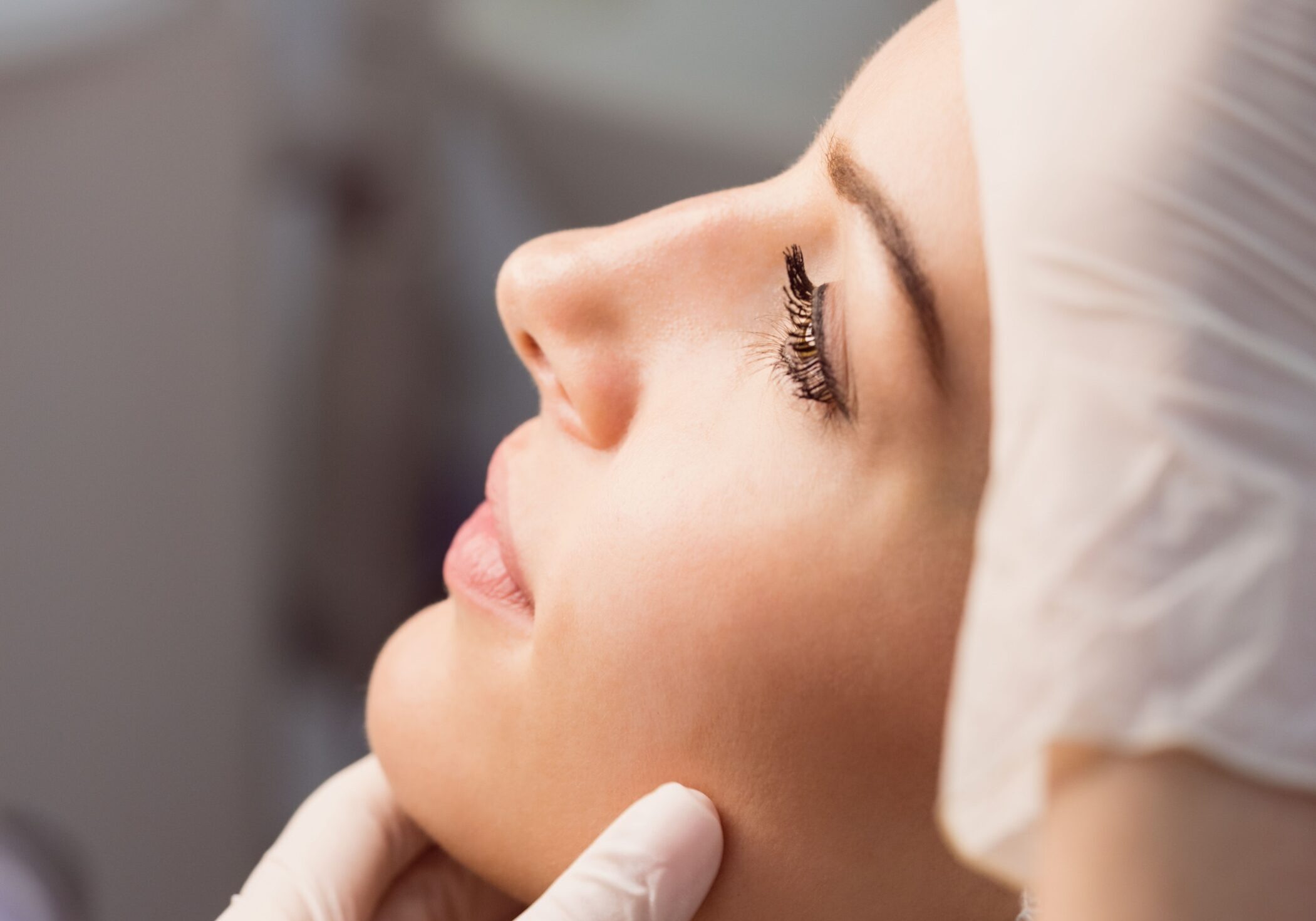 Hands of doctor examining womans face for cosmetic treatment at clinic